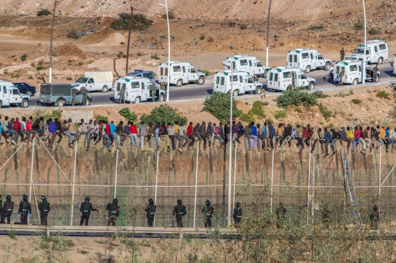 Беженцы и мигранты из африканских стран, расположенных южнее Сахары, пытаются пересечь пограничное заграждение из плоской колючей проволоки, отделяющее Марокко от испанского анклава Мелилья. (Хосе Палазон / GlobalPost).