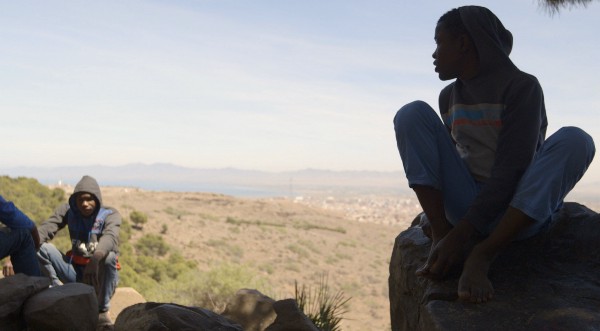 Четырнадцатилетний Бени сидит на камне на окраине лесного марокканского лагеря. Вдалеке виден испанский анклав Мелилья. (Изабелла Александр / GlobalPost) 