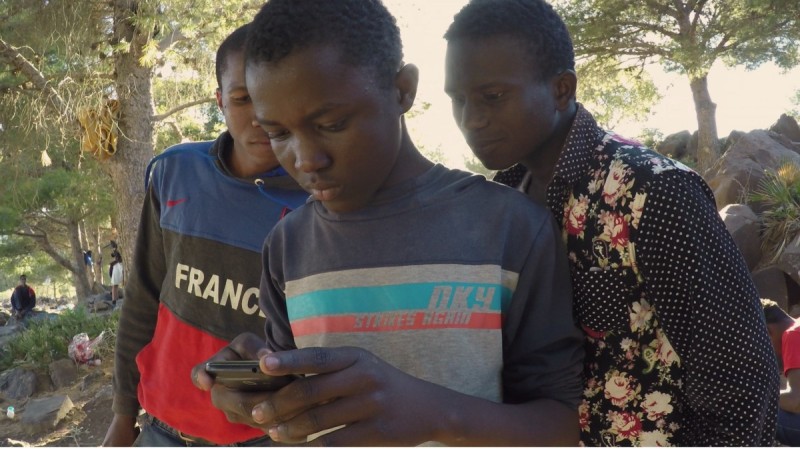 В лагере Бени и двое мальчишек разглядывают фотографии немногих счастливчиков, успешно перебравшихся в Европу. (Изабелла Александр / GlobalPost).